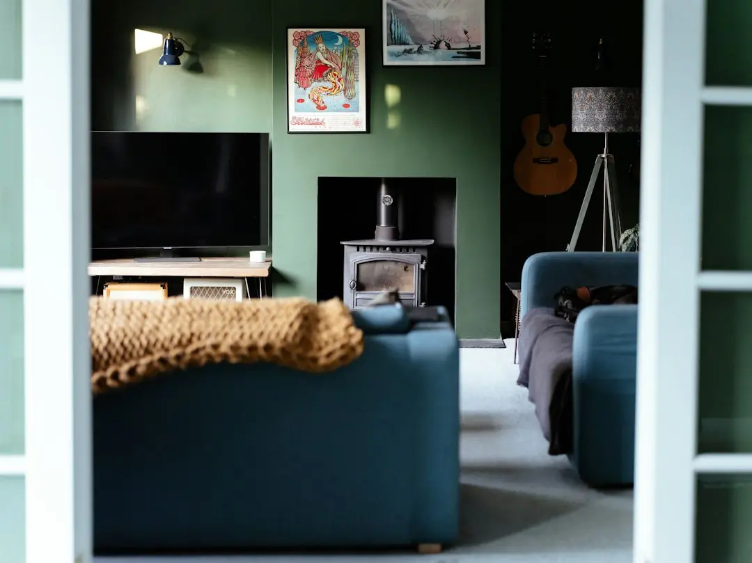 Un salon aux murs verts avec un téléviseur, un canapé bleu et un poêle, pour comprendre Xenon IPTV